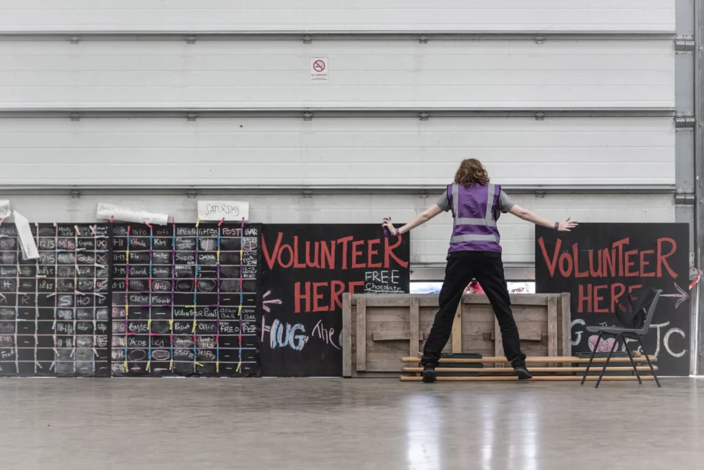 A volunteer standing in front of two signs that target potential volunteers