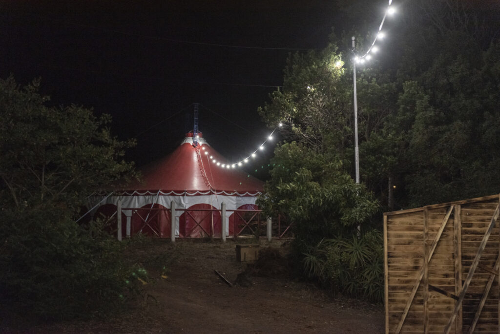 A secluded circus tent with an intriguing chain of lights leading the path 