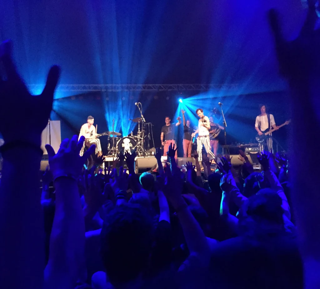 A live band playing on stage with a cheering crowd